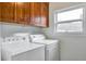 A laundry room with a washer and dryer, wooden cabinets above, and a window for natural light at 14050 W 8Th Ave, Golden, CO 80401