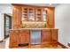 Stylish bar area with custom wood cabinets, glass shelving, stone backsplash, and granite countertops at 36920 Forest Trl, Elizabeth, CO 80107