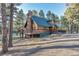 Beautiful exterior with a wooden deck, stone chimney, and large windows, capturing natural light at 36920 Forest Trl, Elizabeth, CO 80107