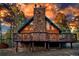 Stunning exterior view of a wood cabin featuring a stone chimney and wraparound deck in a wooded setting at 36920 Forest Trl, Elizabeth, CO 80107