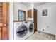 Modern laundry room with front loading washer/dryer, wooden accents, and ample storage at 36920 Forest Trl, Elizabeth, CO 80107