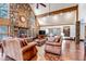 Inviting living room featuring a stone fireplace, wood accents, and comfortable leather seating at 36920 Forest Trl, Elizabeth, CO 80107