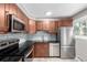 Updated kitchen featuring stainless steel appliances, wood cabinetry, and sleek black countertops at 5635 Nebraska Way, Denver, CO 80224