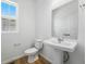 Powder room featuring a pedestal sink, toilet, and a small window with natural light, and vinyl floors at 7291 Prairie Sage Pl, Littleton, CO 80125