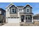 Charming two-story home featuring stone accents, dark gray siding, a black metal roof, and well-manicured landscaping at 7291 Prairie Sage Pl, Littleton, CO 80125