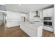 Modern white kitchen featuring a large island, stainless steel appliances, and wood flooring at 7291 Prairie Sage Pl, Littleton, CO 80125
