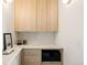 Kitchenette with light wood cabinets, stainless microwave, marble countertop, and tiled backsplash at 3932 Kalamath St, Denver, CO 80211