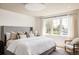 Bright main bedroom with white bedding, large window, wood chair, and tall gray upholstered headboard at 3932 Kalamath St, Denver, CO 80211