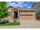 Charming tan-colored home with a two-car garage, a covered entry, and a well-manicured lawn at 1462 Raindrop Way, Castle Rock, CO 80109