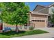 Charming tan-colored home with a two-car garage, a covered entry, and a mature shade tree at 1462 Raindrop Way, Castle Rock, CO 80109