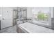 Bathroom featuring a soaking tub with a glass enclosed shower and stone tile surround near window at 4825 S Ammons St # 102, Littleton, CO 80123