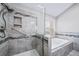 Modern bathroom featuring glass enclosed shower with a soaking tub and stone tile surround at 4825 S Ammons St # 102, Littleton, CO 80123
