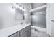 Bathroom featuring a vanity with a stone countertop, decorative mirror and shower with glass doors at 4825 S Ammons St # 102, Littleton, CO 80123