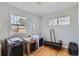 Bright bedroom featuring hardwood floors, multiple windows, and three animal crates with a dog treadmill at 2625 S Linley Ct, Denver, CO 80219