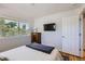 Sunlit bedroom featuring a comfortable bed, wood floors, TV, and a picturesque window view at 2625 S Linley Ct, Denver, CO 80219