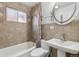 Tiled bathroom with shower-tub, pedestal sink, round mirror, and frosted window at 4825 Estes St, Arvada, CO 80002