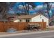 Ranch style home with wooden fence, wagon wheel accents, and mature trees at 4825 Estes St, Arvada, CO 80002