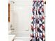 Bathroom includes a white tub and shower combo with tiled walls and a colorful geometric pattern shower curtain at 633 W 114Th Way, Northglenn, CO 80234