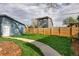 Expansive backyard featuring a grass area, a paved walkway, wooden fence, and a blue outbuilding at 3731 N Race St, Denver, CO 80205
