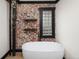Charming bathroom features exposed brick, floating shelves, a glass block window, and free-standing tub at 3731 N Race St, Denver, CO 80205