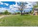 Expansive backyard with lush green grass, mature trees, and various outbuildings at 10220 W Montgomery Ave, Littleton, CO 80127