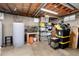 Unfinished basement with exposed ceiling, storage shelves, and a water tank at 10220 W Montgomery Ave, Littleton, CO 80127