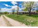 Spacious home with a large, well-manicured front lawn and mature trees under a partly cloudy sky at 10220 W Montgomery Ave, Littleton, CO 80127