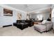 Open-concept living area with a white brick accent wall, plush seating, and views into another room at 10220 W Montgomery Ave, Littleton, CO 80127