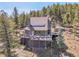 Multi-level mountain home with a large deck perfect for entertaining and a fully fenced yard surrounded by tall pine trees at 6574 Olympus Dr, Evergreen, CO 80439