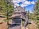 Stunning multi-level house, surrounded by trees, boasting a two-car garage and multiple decks with stairway access at 6574 Olympus Dr, Evergreen, CO 80439