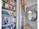 Charming library nook with floor-to-ceiling bookshelves, a wooden ladder, and a cozy porthole window at 6574 Olympus Dr, Evergreen, CO 80439