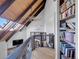 Loft featuring wood ceiling with skylights, metal railings, a stone fireplace, and built-in bookshelves at 6574 Olympus Dr, Evergreen, CO 80439