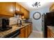 Galley kitchen featuring tile backsplash, granite countertops, stainless steel appliances, and natural wood cabinets at 7780 W 38 Th Ave # 203, Wheat Ridge, CO 80033