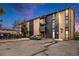 Multi-story apartment building with balconies, dark accents, a parking lot, and landscaping at 865 S Quebec St # 103B, Denver, CO 80247