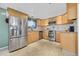 Well-lit kitchen featuring tile floors, stainless steel appliances and natural wood cabinets at 1671 S Chase St, Lakewood, CO 80232