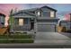 Charming two-story home with stone accents and a well-manicured lawn at dusk at 17487 E 89Th Way, Commerce City, CO 80022