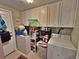 Well-lit laundry room with white appliances, overhead cabinets, and tile floors at 6060 Locust St, Commerce City, CO 80022