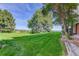 Lush backyard with a vibrant green lawn, mature trees, and a view of the surrounding landscape at 539 Wright St # 102, Lakewood, CO 80228