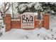 Snow-covered Riva Ridge Apartment complex sign with brick pillars and landscaping at 539 Wright St # 102, Lakewood, CO 80228