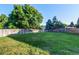 Vast backyard with lush green grass, framed by a wooden privacy fence and mature trees at 8538 W Glasgow Pl, Littleton, CO 80128