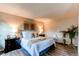 Bright bedroom with wood floors, two side tables with lamps and large bed topped with pillows and blanket at 8538 W Glasgow Pl, Littleton, CO 80128