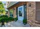 Close-up of front door with storm door, brick surround, and manicured bushes at 8538 W Glasgow Pl, Littleton, CO 80128