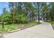 Exterior view of a long driveway leading to a three-car garage, surrounded by lush trees and mature landscaping at 929 Tenderfoot Dr, Larkspur, CO 80118