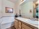Bright bathroom with double sinks, bathtub, neutral tile, and large mirror at 6626 S Reed Way # A, Littleton, CO 80123