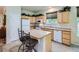 Bright kitchen with an island, white appliances, wood cabinets and tile floor at 6626 S Reed Way # A, Littleton, CO 80123