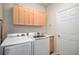 Bright laundry room featuring a white washer and dryer, wood cabinets, sink, and access door at 6626 S Reed Way # A, Littleton, CO 80123