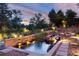 Outdoor pond with stone accents and waterfall features, illuminated at dusk with uplighting at 73 Falcon Hills Dr, Highlands Ranch, CO 80126