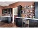 A stylish bar area with sleek black cabinets, granite countertops, glass shelving and a wine cooler at 73 Falcon Hills Dr, Highlands Ranch, CO 80126