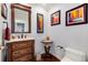 Elegant powder room with a furniture-style vanity, decorative mirror, hardwood floors, and stylish artwork on the walls at 73 Falcon Hills Dr, Highlands Ranch, CO 80126