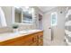 Well-lit bathroom with a single sink, wood vanity, window for light and a shower in the background at 5436 S Versailles Way, Aurora, CO 80015
